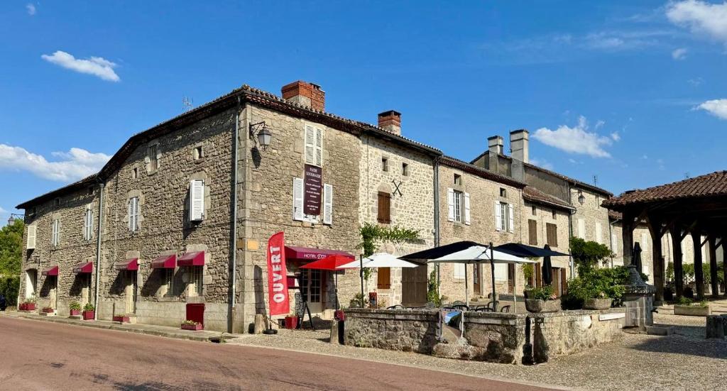 a large brick building with umbrellas next to a street at Douce Demeure - Hôtel-Restaurant de Mortemart in Mortemart