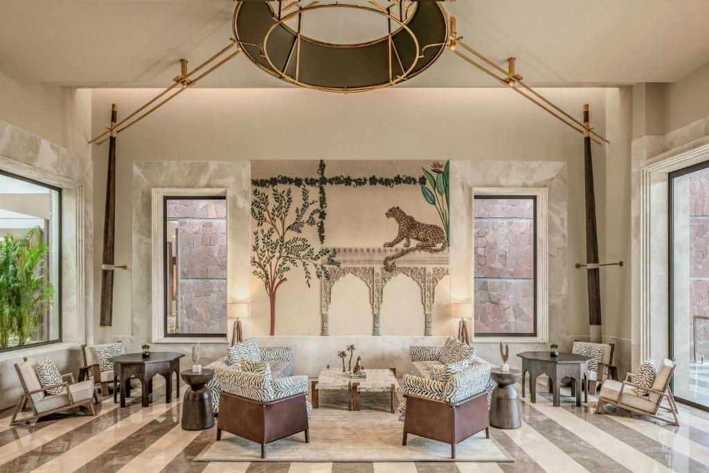 a living room with a couch and chairs and a chandelier at JW Marriott Ranthambore Resort & Spa in Sawāi Mādhopur