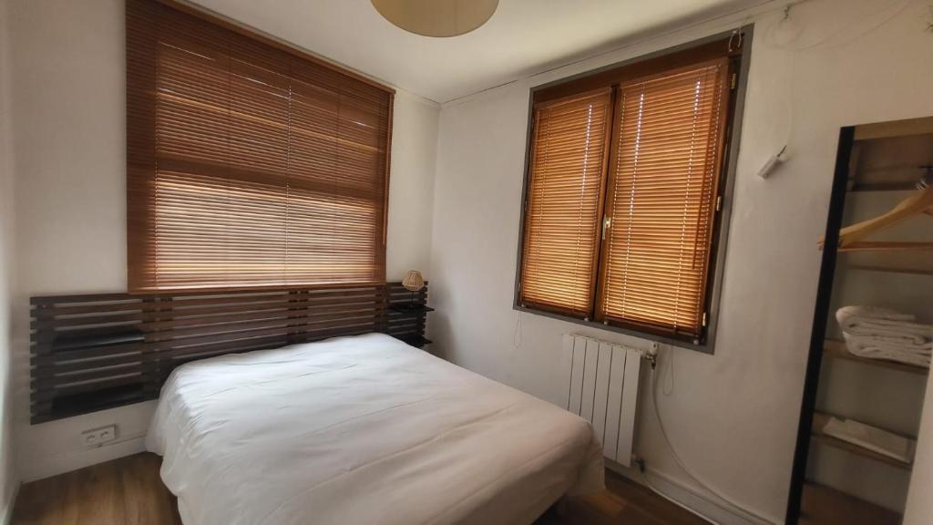 a small bedroom with a bed and two windows at Chambre 8 in Le Trait