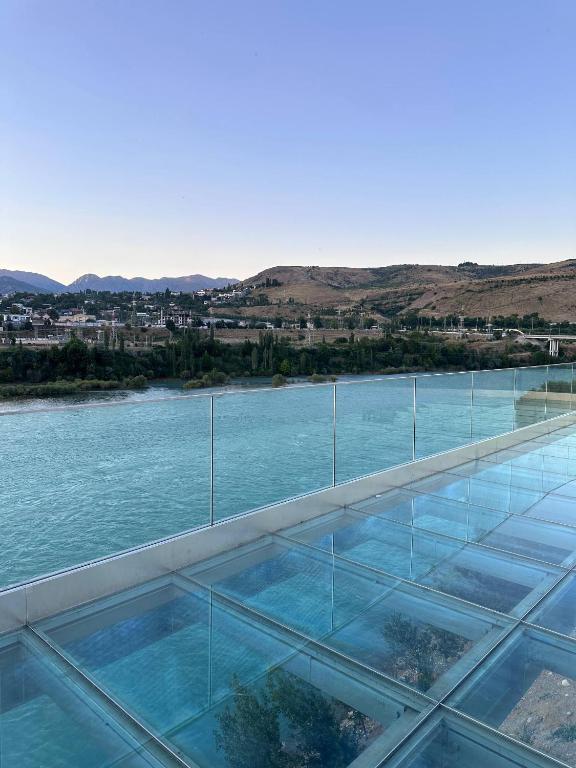 a glass house on the water with a view at Chorvoq Darvozasi touristic complex in Chorwoq