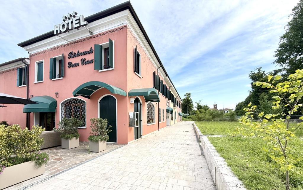 ein rosafarbenes Gebäude mit einem Bürgersteig davor in der Unterkunft Hotel Gran Casa in Oderzo