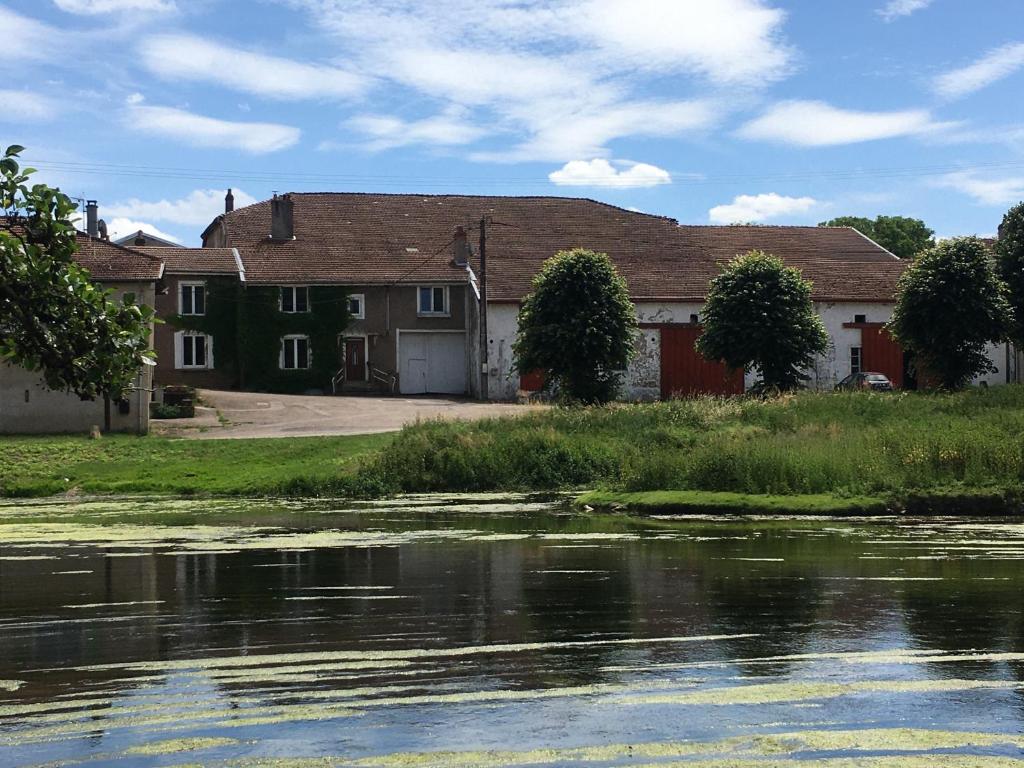 a house sitting next to a body of water at La maison des ponts in Pont-sur-Madon