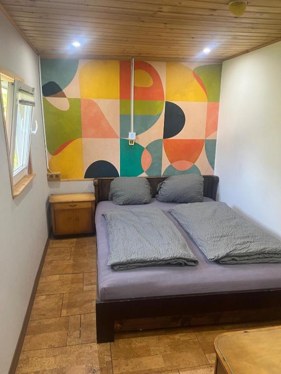 a bed in a room with a colorful wall at wiesenhimmel cozy, Tiny house with sauna in Forchtenberg