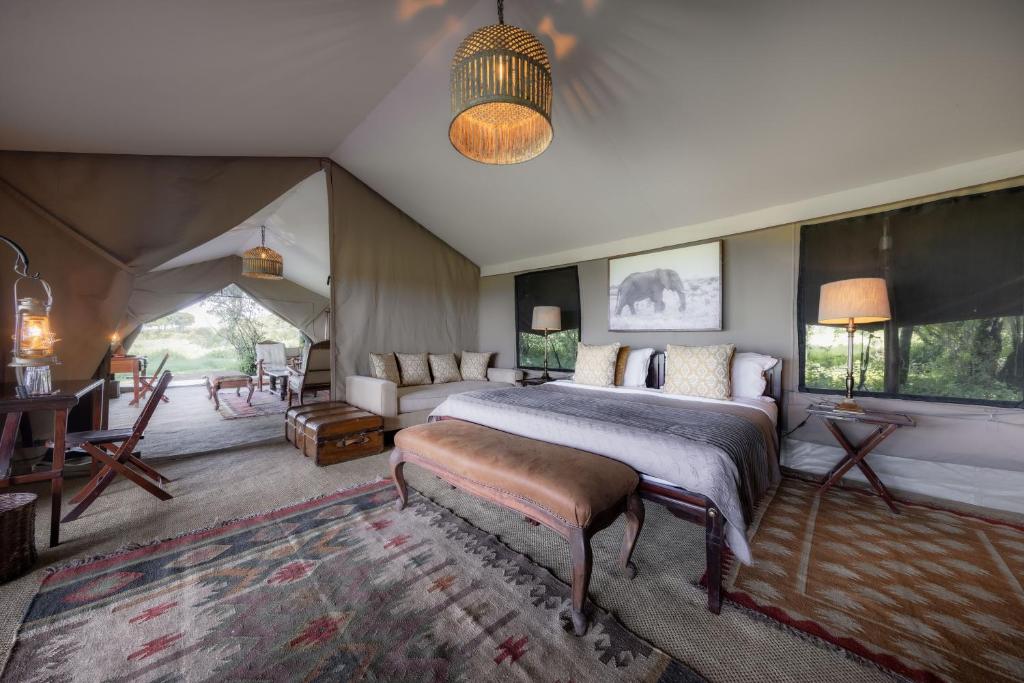 a bedroom with a bed and a couch in a tent at Elephant Pepper Camp in Masai Mara