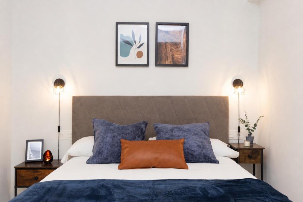 a bedroom with a bed with blue pillows and two lights at Xena Cucuraza by BeValle in Panticosa