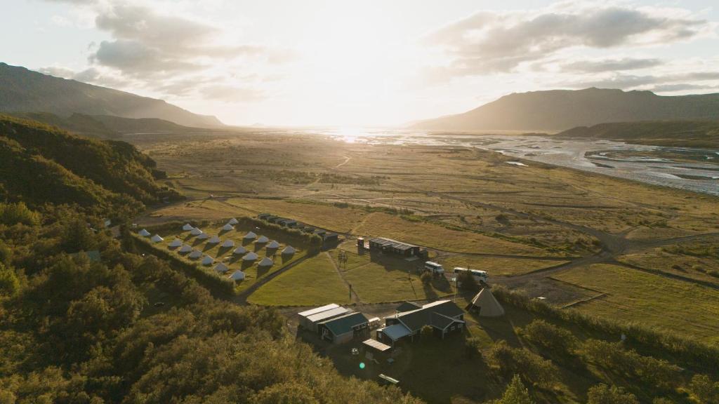 an aerial view of a house in a field with the sunset at Volcano Huts Þórsmörk in Thorsmork