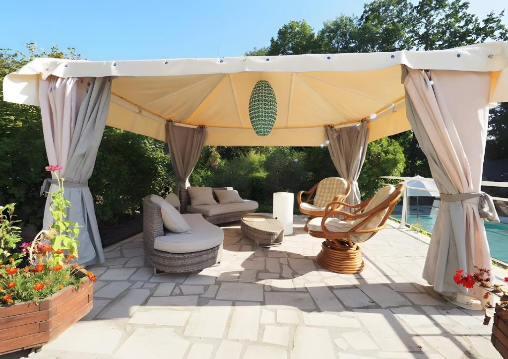 a gazebo with chairs and tables on a patio at La Bruyère-Maison d'hôtes-Piscine in May-sur-Orne