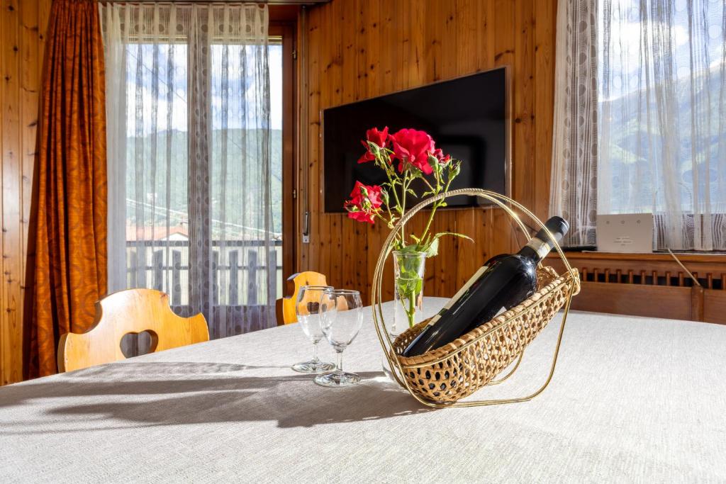 a table with a basket with a vase of flowers and wine glasses at Casa Lena in Colorina