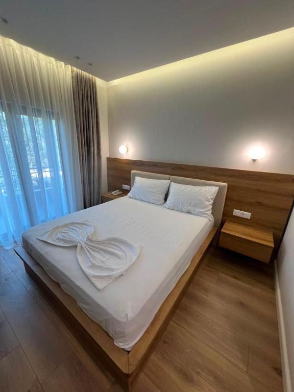 a bedroom with a large bed with white sheets and pillows at Hotel Restorant Riza in Tirana