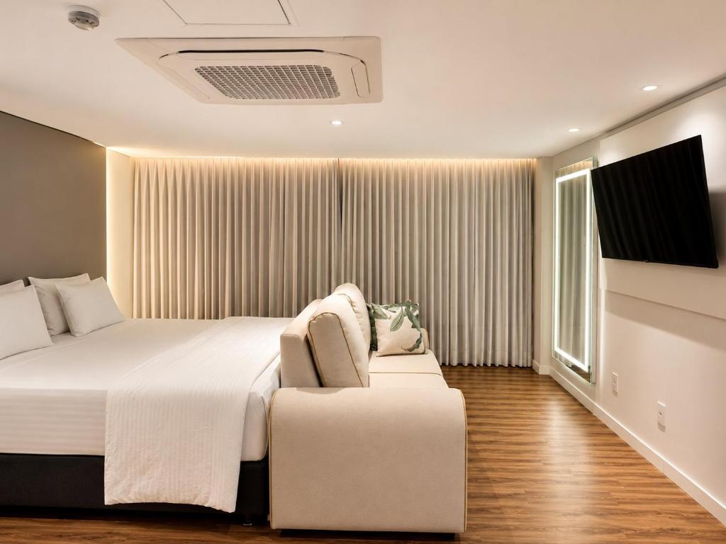 a bedroom with a large bed and a chair at Hotel Greenville by Slim Hotéis in Primavera do Leste