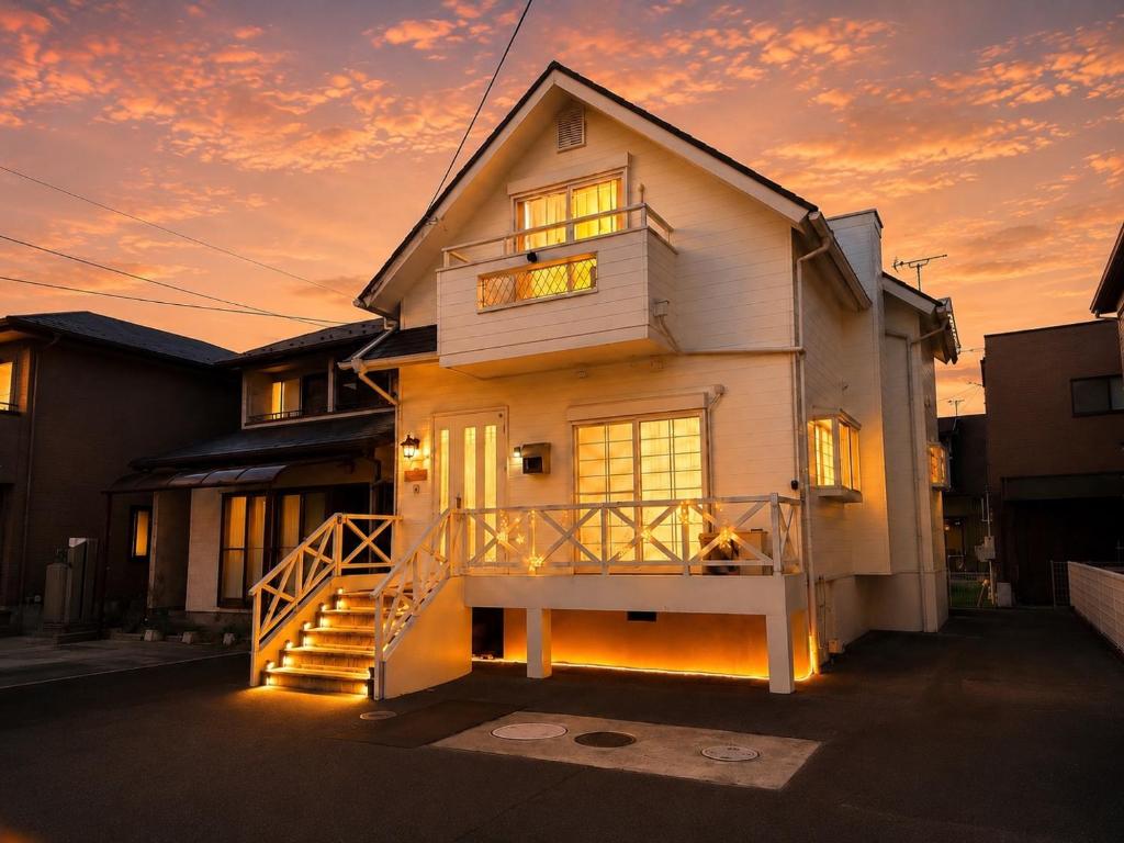 a house with a staircase in front of a sunset at Daiwa House BBQ 琵琶湖徒步3分 無料駐車4台プロジェクター in Takashima