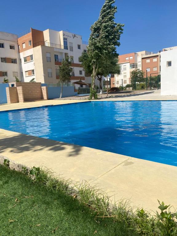 a large blue swimming pool in front of some buildings at Super appartement in Hauara