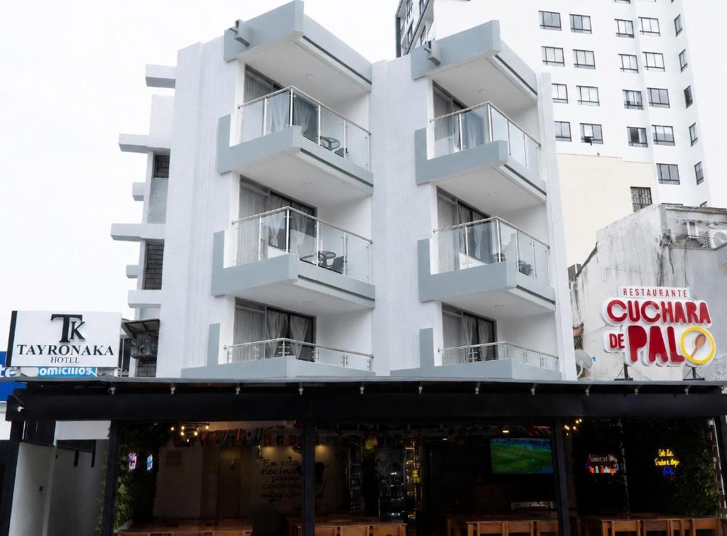 a white building with a restaurant in front of it at Hotel Tayronaka in Santa Marta