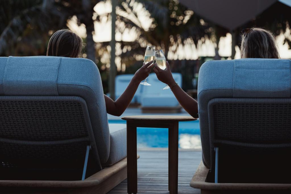 two women sitting in chairs drinking a glass of wine at Sorobon Bay Hotel in Kralendijk
