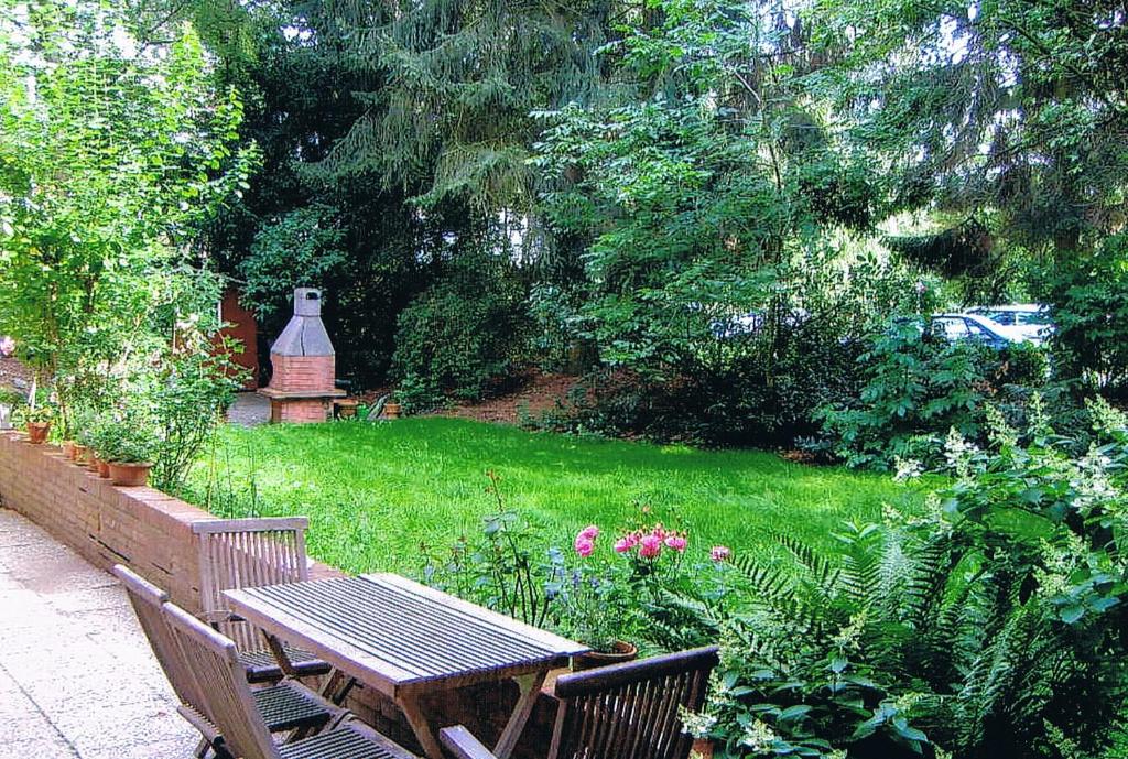 un banco de madera sentado en medio de un jardín en Ferienwohnung in Hamburg West, en Hamburgo