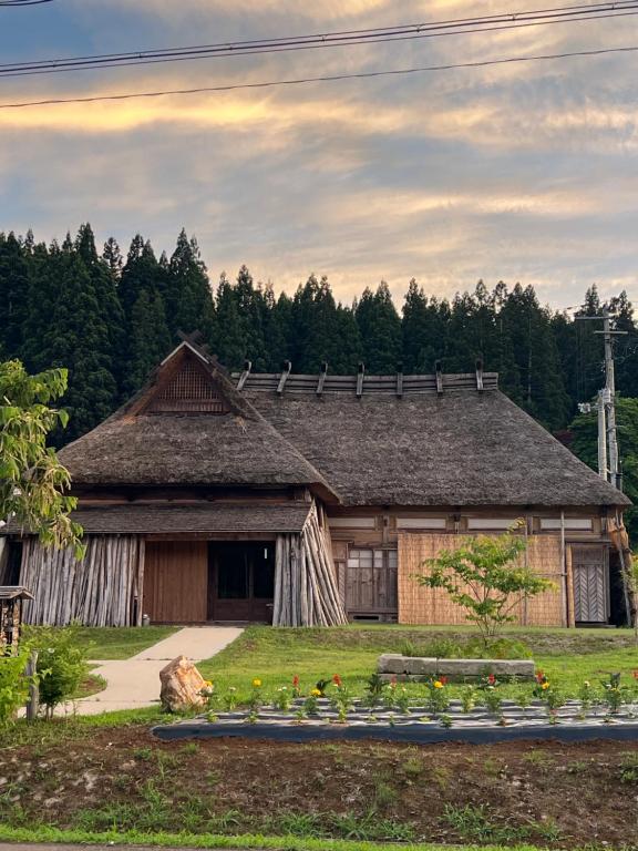 a house with a bunch of flowers in front of it at うご八かやぶ㐂 in Narazaki