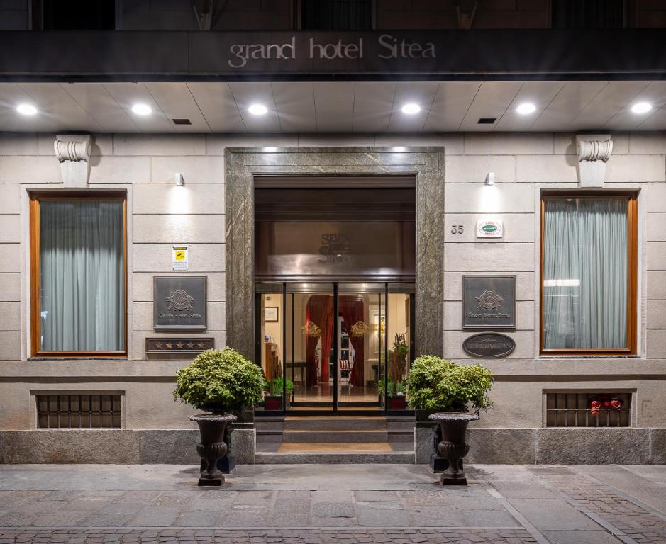 a hotel entrance with two potted plants in front of it at Grand Hotel Sitea in Turin