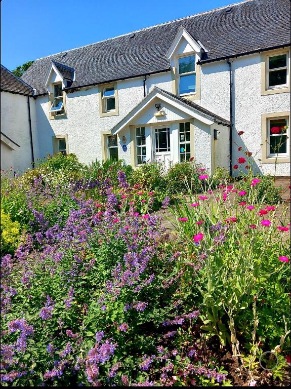 a house with a garden of flowers in front of it at Hartfield House Hostel in Applecross