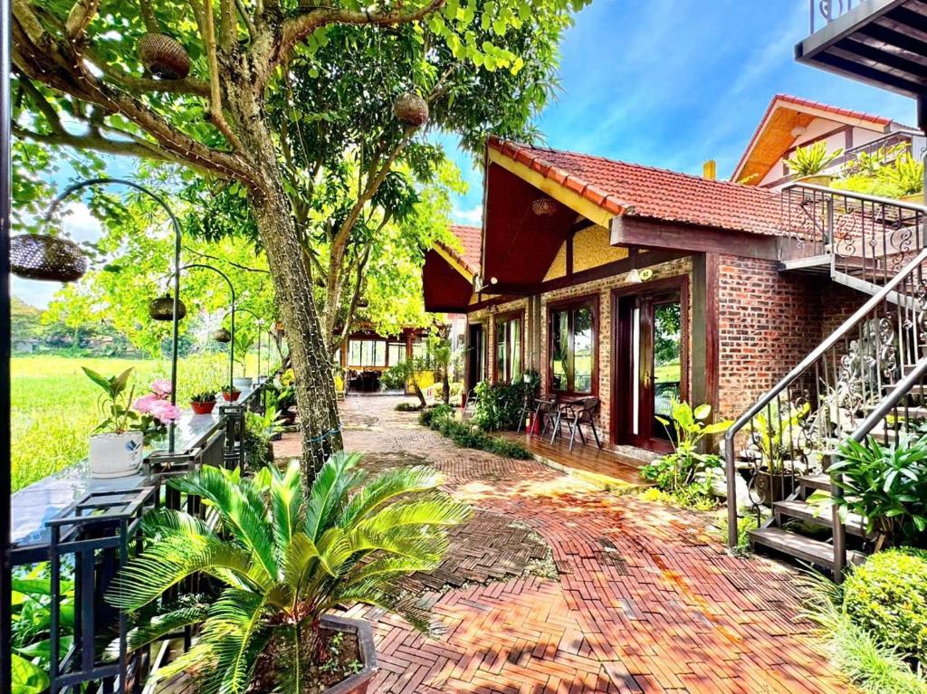 a brick house with a patio and a tree at L'Ananas Garden Homestay in Vũ Lâm
