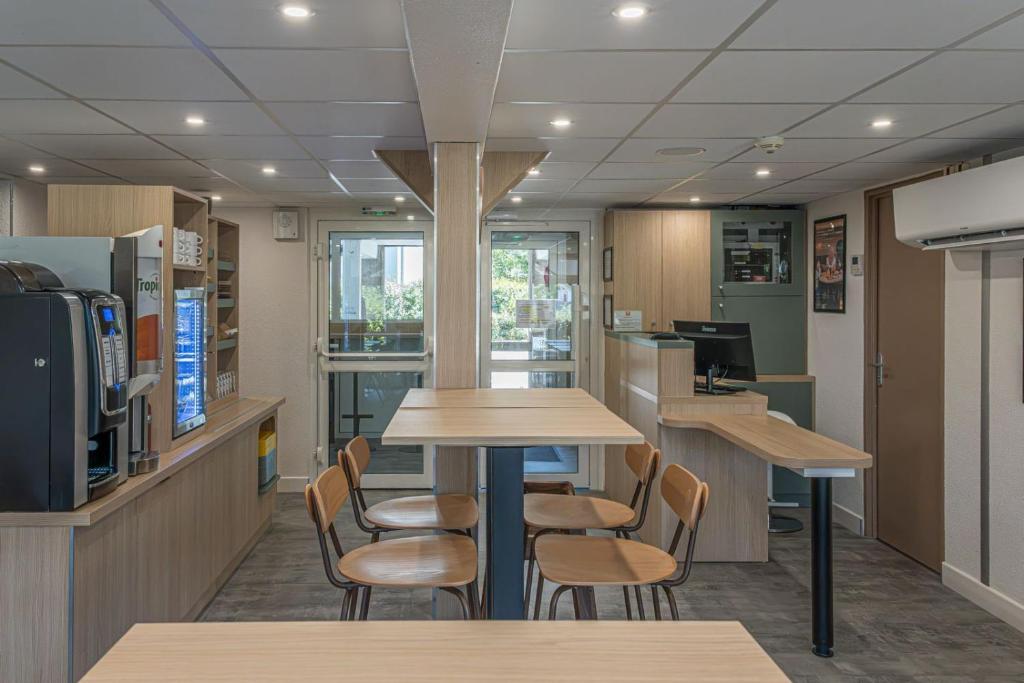a cafeteria with tables and chairs and a tv at Premiere Classe Rodez in Rodez