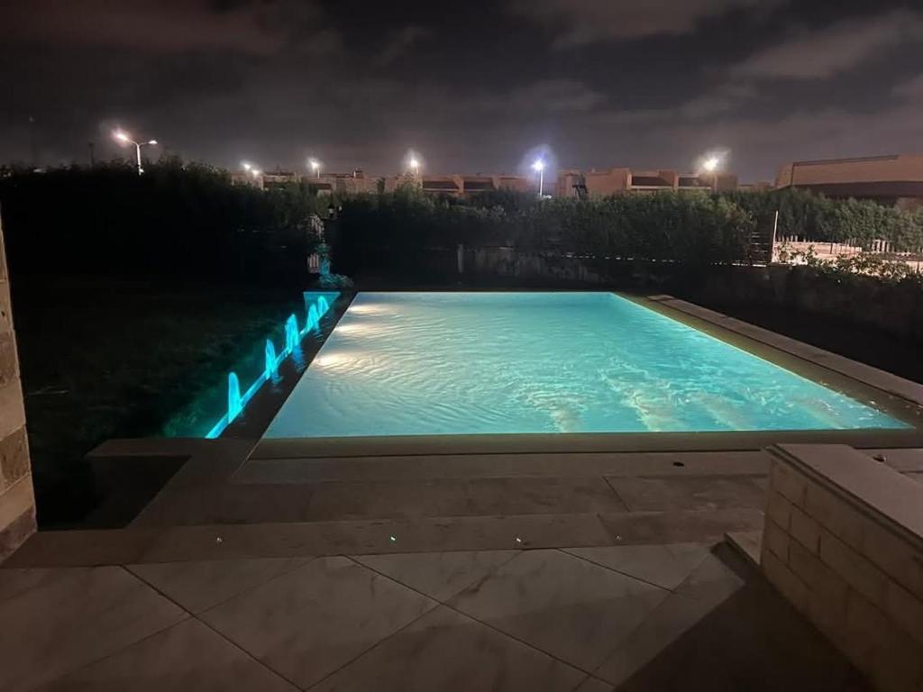 a swimming pool at night with lights on at شاليه بقرية الفيروز in Qaryat Shurūq