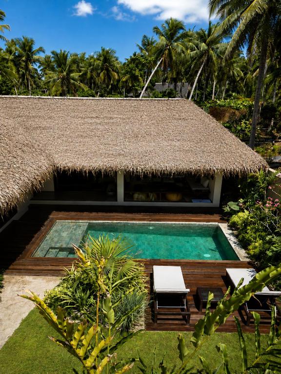 a resort with a swimming pool and a straw roof at Nayma Villas in General Luna