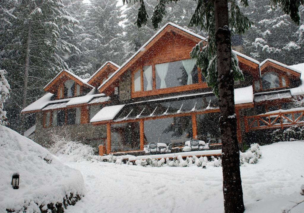 a house covered in snow in the woods at Costa Serena Aparts & Spa in Villa La Angostura