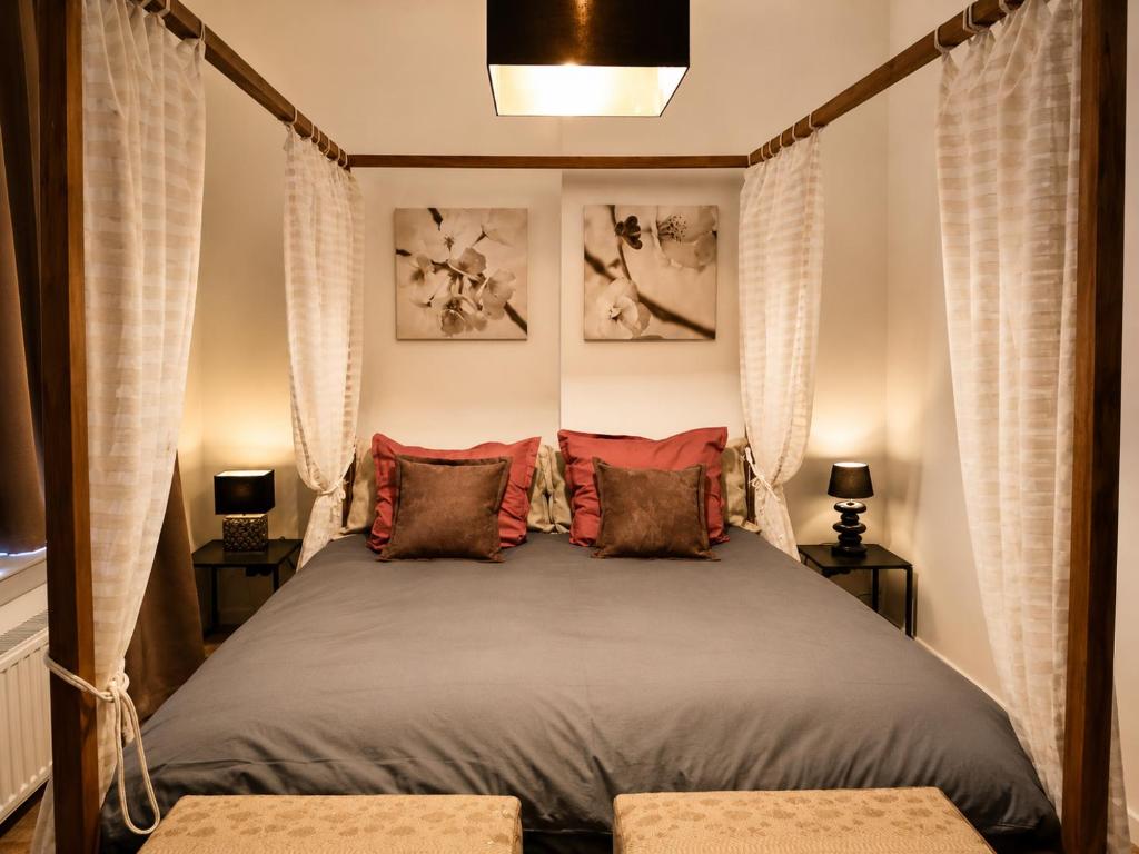 a bedroom with a canopy bed with red pillows at The Manhattan Luxury suite in Jumet