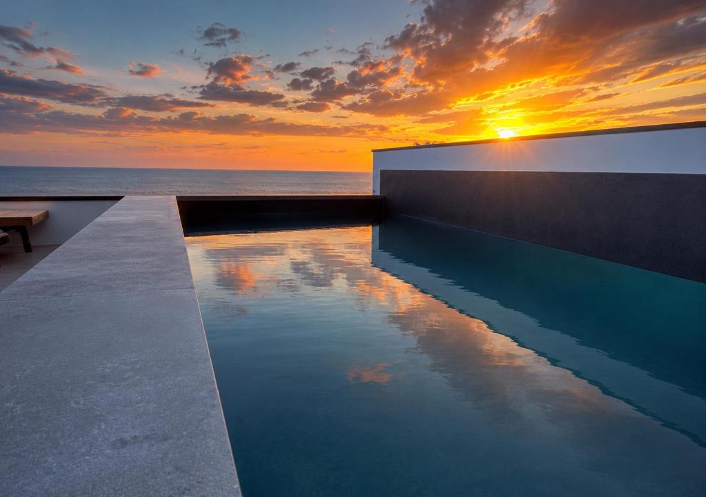 a swimming pool with a sunset in the background at Casa do Sol by Amazing Madeira in Jardim do Mar