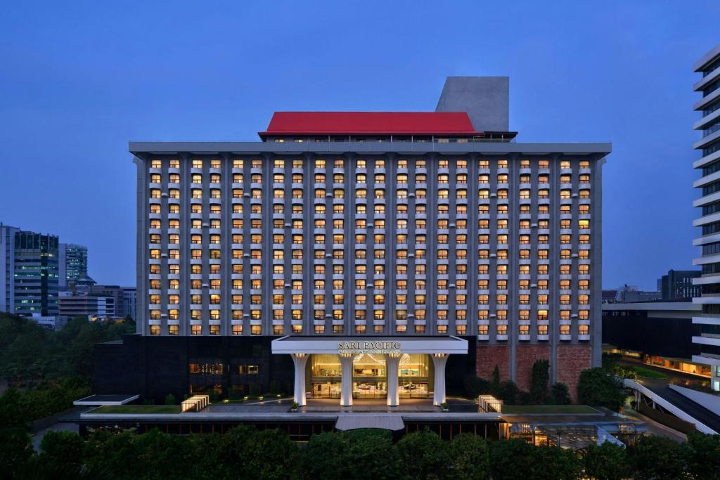 a large hotel building with a lit up building at Sari Pacific Jakarta, Autograph Collection in Jakarta