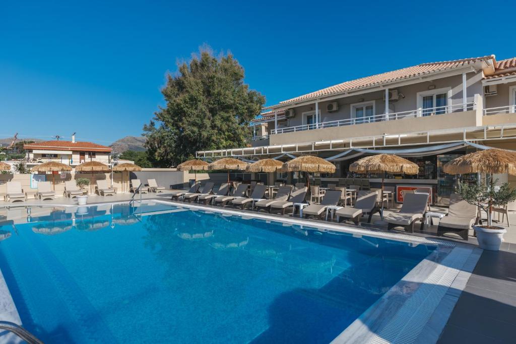 a swimming pool with chairs and umbrellas in front of a hotel at Esperia Hotel in Laganas