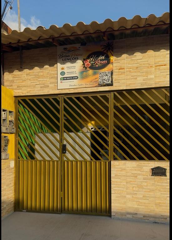 a building with a garage door with a sign on it at Pousada e Hostel das Rosas in Barreirinhas