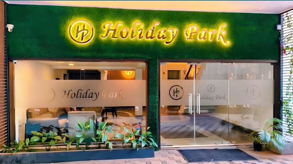 a shop front with a neon sign in the window at Hotel Holiday Park,Thalassery in Green Island