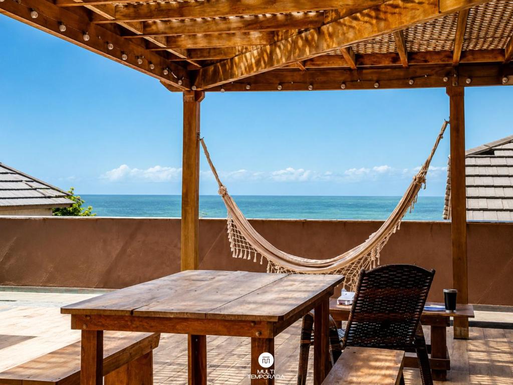 a hammock and a table and chairs on a beach at Residencial La Ferrugem - Garopaba/SC in Garopaba
