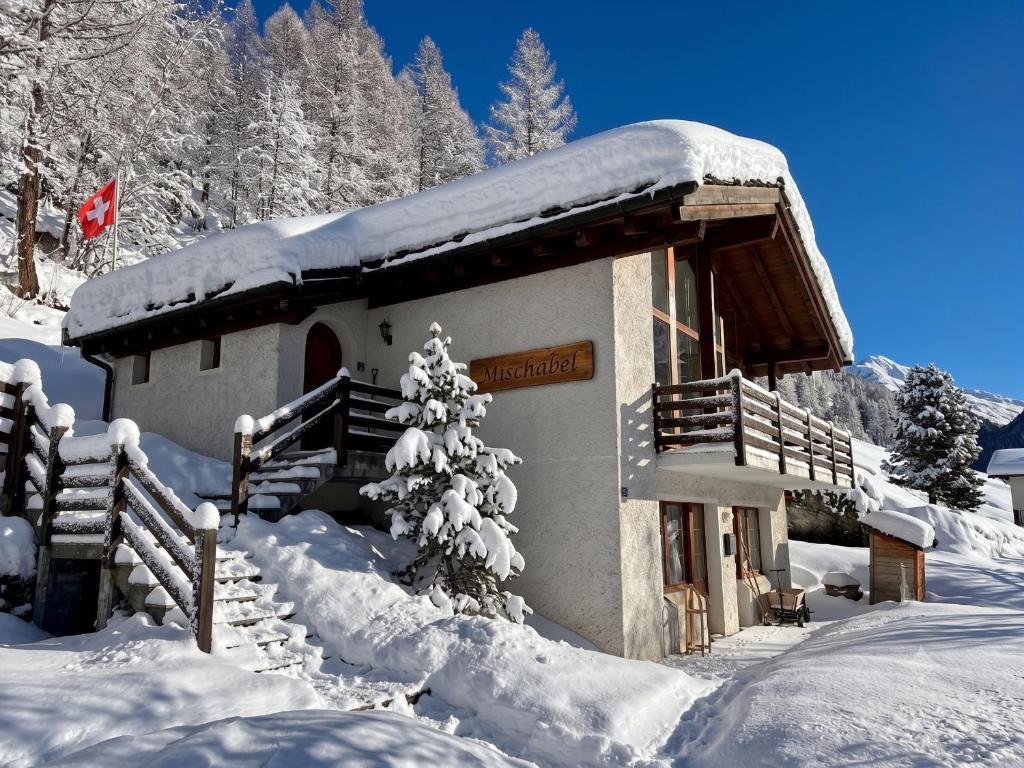 a snow covered building with a tree in front of it at Chalet Mischabel in Saas-Grund