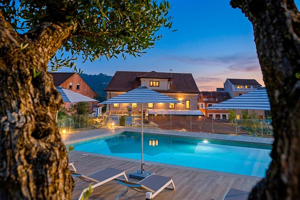 a swimming pool with chairs and umbrellas in front of a house at Pardavila 57 Slow Hotel in Marín