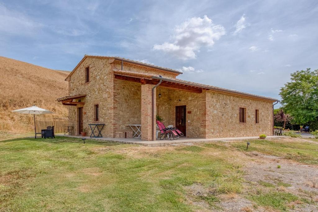 a brick house with a person sitting outside of it at La Quinta Decima Bioagriturismo in Fattoria Spedaletto