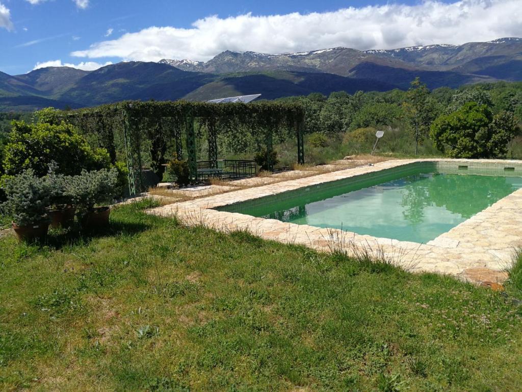 a swimming pool in a yard with mountains in the background at Finca El Ropero Eco-friendly house in Villanueva de la Vera