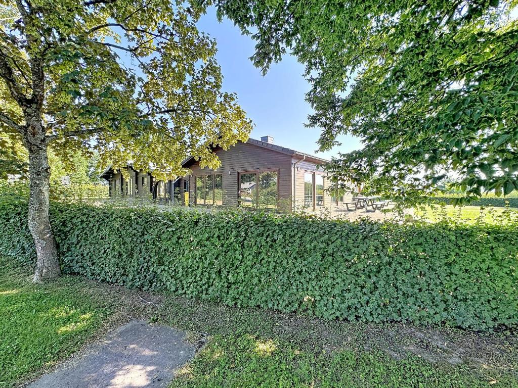 a house behind a hedge in front of a building at Le Refuge du Trappeur in Hour