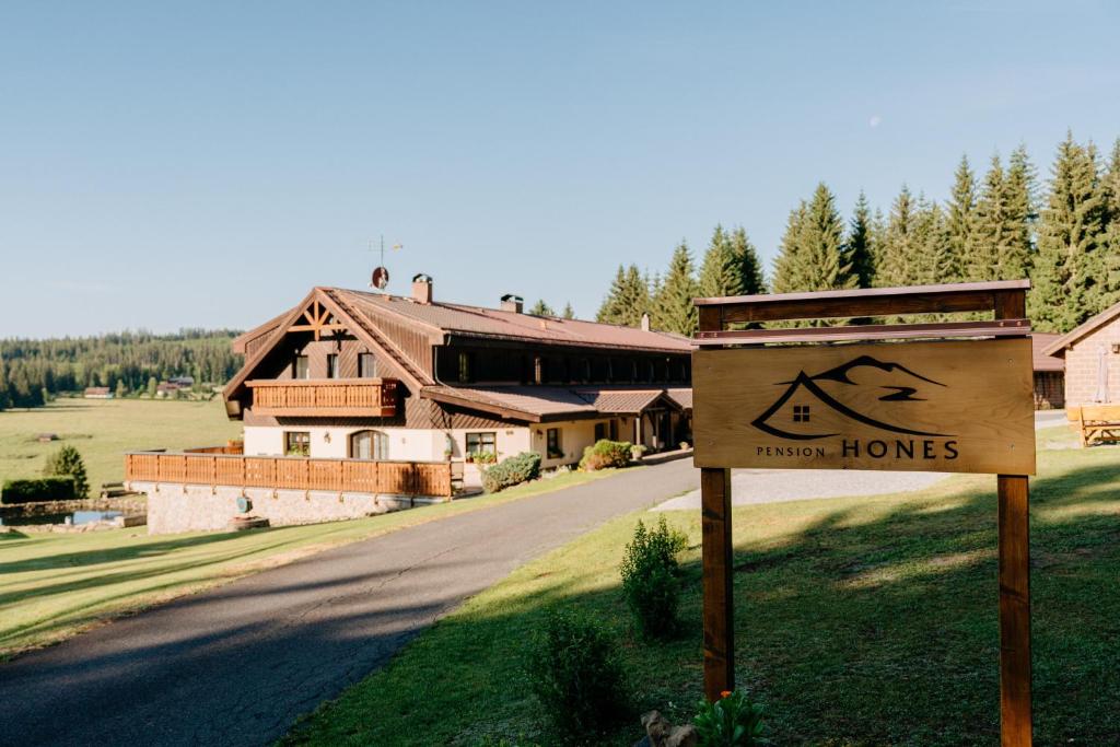 a sign on the side of a road in front of a house at Pension Hones in Horská Kvilda