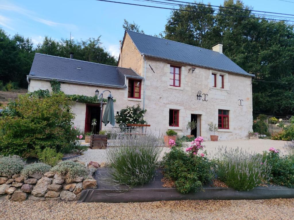 a white house with red windows and a garden at Le Logis Rabelaisien in Bourgueil