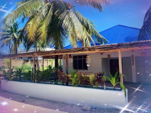 a house with a palm tree in front of it at Mambo Leo Hostel in Paje