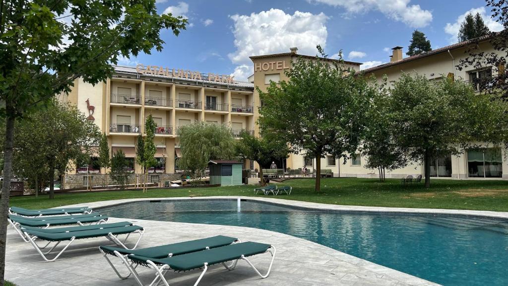 a hotel with a swimming pool with chairs and a building at Hotel Catalunya Park in Ribes de Freser