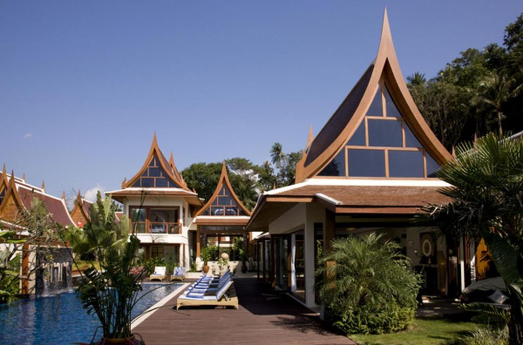 a building with a swimming pool next to a resort at Dhevatara Cove in Lipa Noi