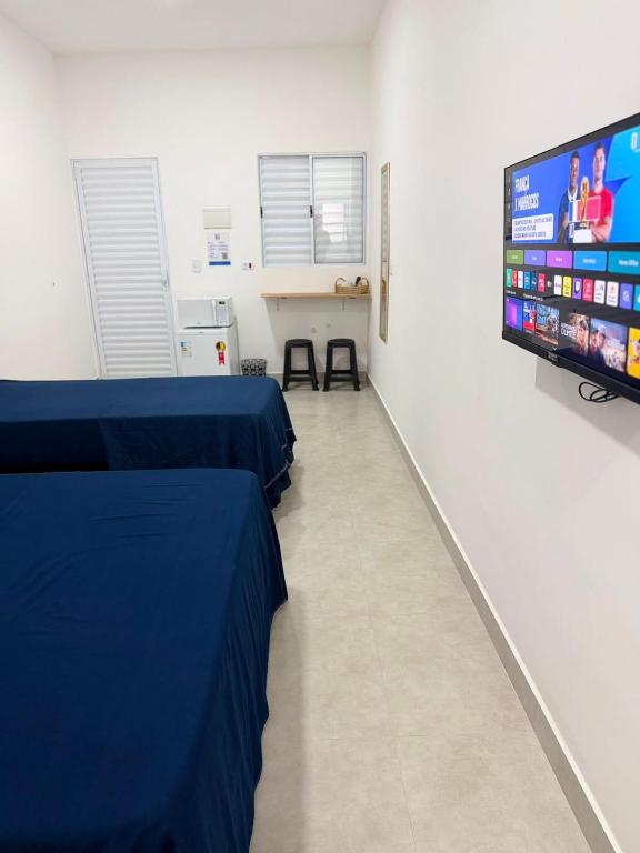 a hospital room with two beds and a flat screen tv at Suítes confortáveis próximo ao Sesc in Bertioga