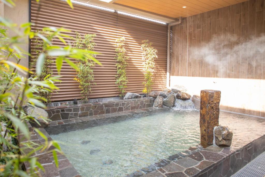 a swimming pool with a waterfall in a building at Dormy Inn Kobe Motomachi Natural Hot Springs in Kobe