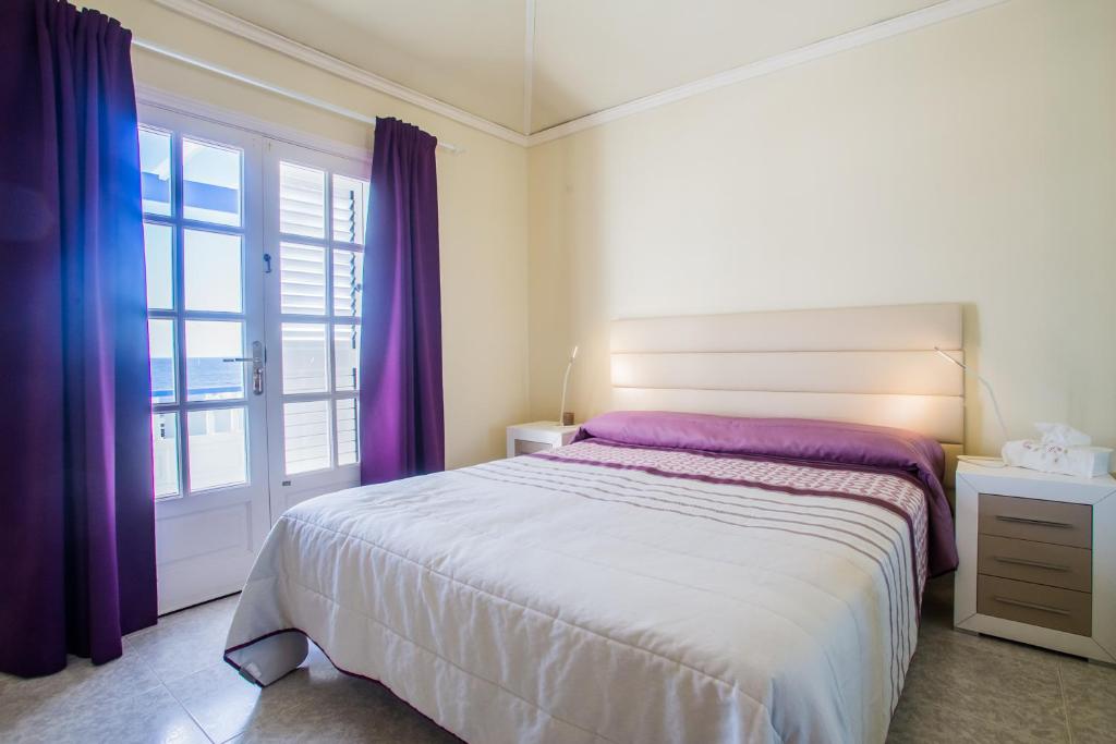 アリエタにあるVilla Tabaibaのベッドルーム1室(紫色のカーテンと窓付きのベッド1台付)