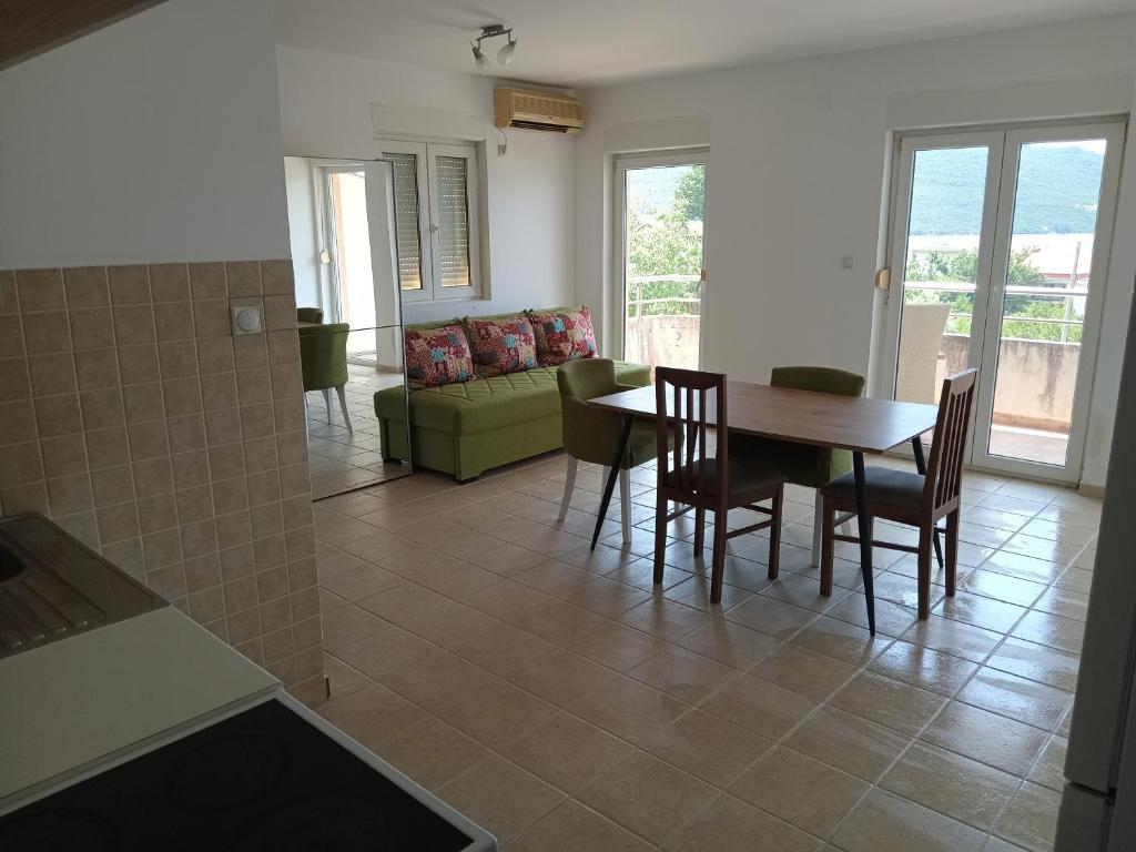 a dining room and living room with a table and chairs at Kumbor S in Herceg-Novi