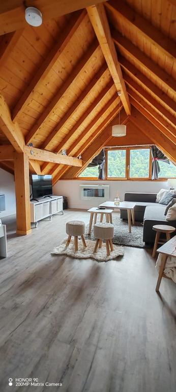 a large living room with wooden ceilings and tables at L'insolite comblée in Ustou