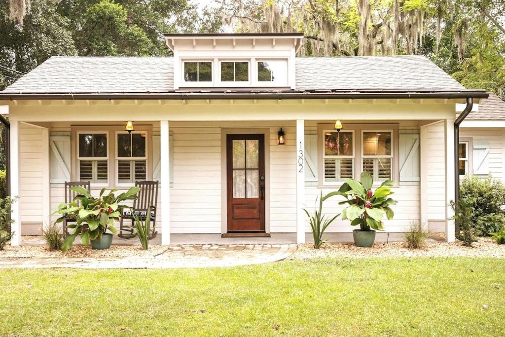 a white house with a front door and two plants at Pigeon Point Cottage with State Park Beach Pass in Beaufort